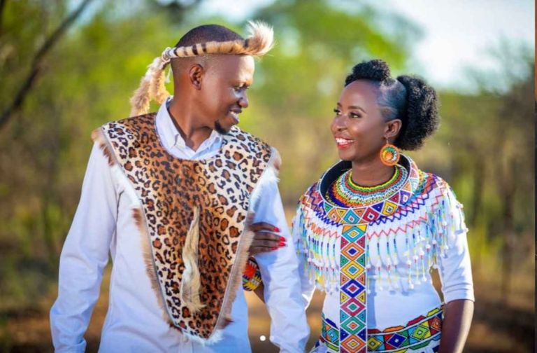 African culturally dressed smiling man and woman looking at each other